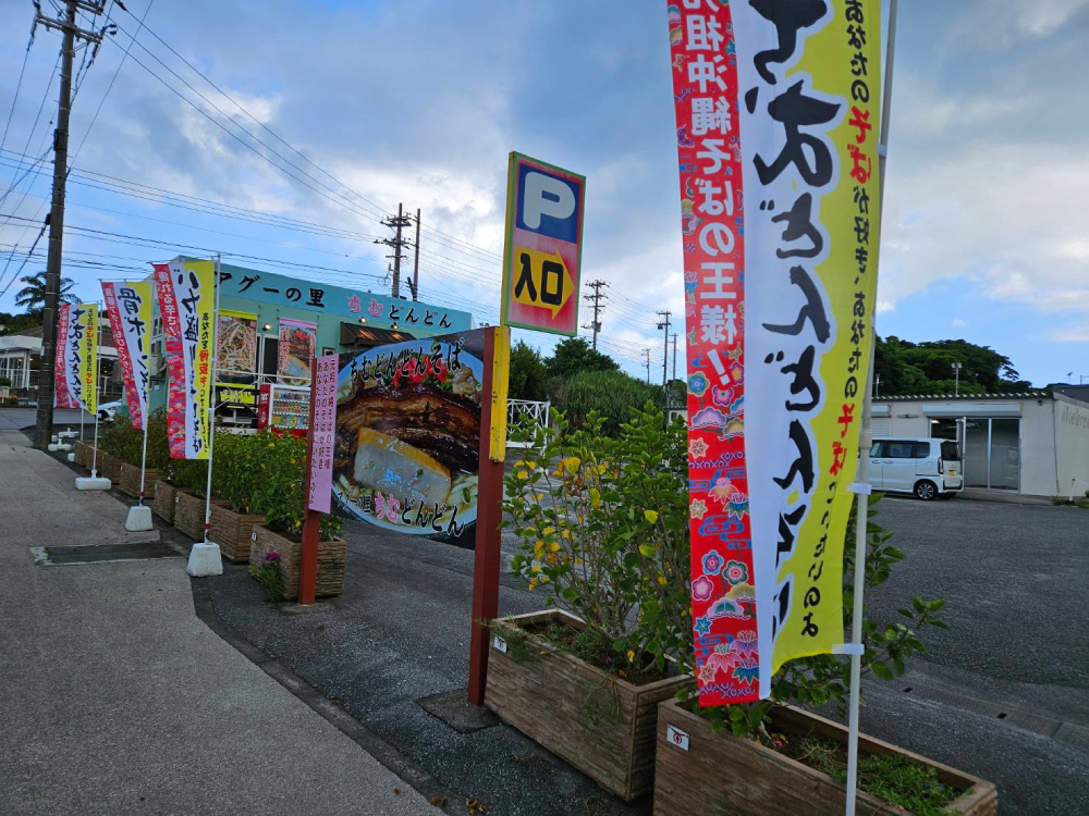 店舗前の旗と広々駐車場｜本部町沖縄そば ちむどんどん